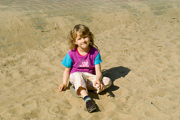 Image showing The girl sits on sand