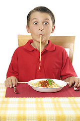 Image showing Child sucking long pasta through lips