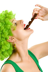 Image showing closeup of an attractive woman with green wig biting a chocolate bar