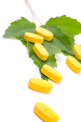 Image showing yellow vitamin pills over green leaves