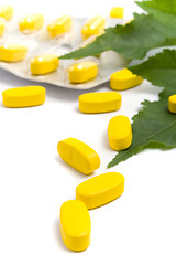 Image showing yellow vitamin pills and green leaves