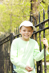 Image showing Smiling boy holding on to fence