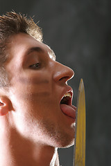 Image showing Soldier licking knife blade