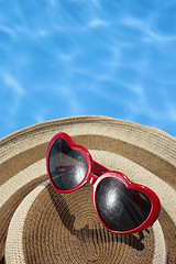 Image showing Red Sunglasses and Hat by a Blue Pool