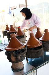 Image showing muslim woman cooking food in tagine morocco