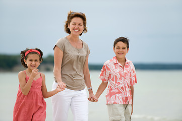 Image showing Mother and kids walking on the beach