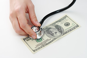 Image showing Doctor holding stethoscope against one hundred u.s. banknote