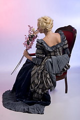 Image showing Beautiful woman sitting on a chair with flowers