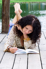 Image showing outdoor portrait of a beautiful woman reading a book 