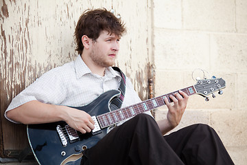 Image showing young man playing guitar outdoors