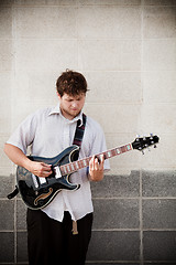 Image showing man playing guitar against wall