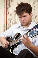 Image showing young man playing guitar outdoors