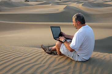 Image showing Man with laptop sitting in the desert.