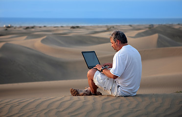 Image showing Man with laptop sitting in the desert.