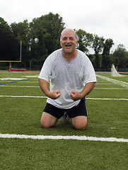 Image showing middle age man stretching and exercising on sports field