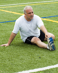 Image showing middle age man stretching and exercising on sports field