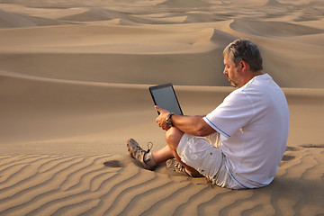 Image showing Man with laptop sitting in the desert.