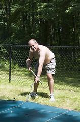 Image showing homeowner removing swimming pool cover at suburban house