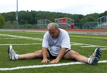 Image showing middle age man stretching and exercising on sports field