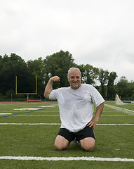 Image showing middle age man stretching and exercising on sports field