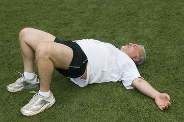 Image showing middle age man stretching and exercising on sports field