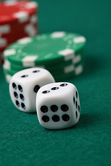 Image showing Pair of gambling die and poker chips on a green surface.