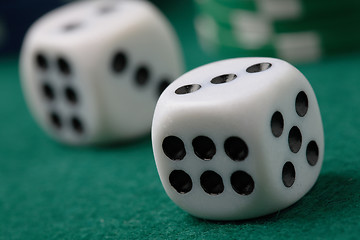 Image showing Pair of gambling die and poker chips on a green surface.