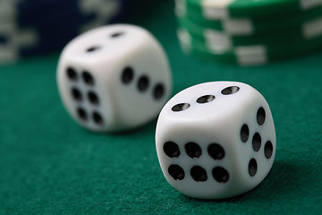 Image showing Pair of gambling die and poker chips on a green surface.