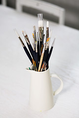 Image showing Set of paintbrushes in jug on a table.