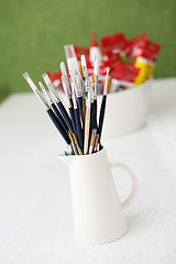 Image showing Paintbrushes and tubes of paint on a table outdoors.