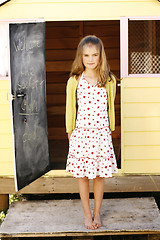 Image showing Portrait of a pretty young girl standing outside her playhouse.
