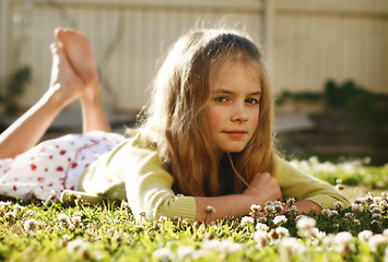 Image showing Pretty young girl lying on the grass amongst flowers.