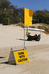 Image showing Swimming caution sign and flag on beach.