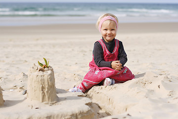 Image showing Smiling little girl playing on the beach. 