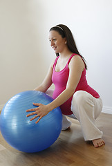 Image showing Young smiling pregnant woman doing squatting exercise with fitne