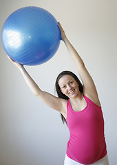 Image showing Young smiling pregnant woman exercising with fitness ball.