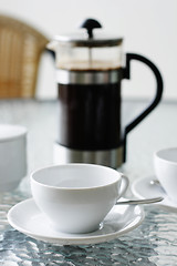 Image showing Black filter coffee and plunger on a glass table.