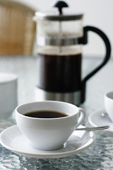 Image showing Black filter coffee and plunger on a glass table.