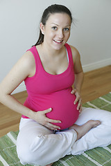 Image showing Young smiling pregnant woman holding her tummy.