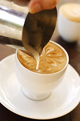 Image showing A barista creating latte coffee art.