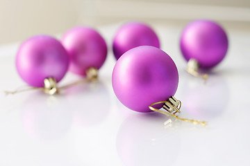 Image showing Purple  Christmas baubles on a glass table.