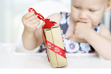 Image showing Little girl carefully opening Christmas gifts.