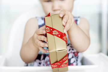 Image showing Little girl carefully opening Christmas gifts.