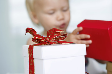 Image showing Little girl carefully opening Christmas gifts.