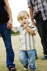 Image showing hild walking with parents in a park.