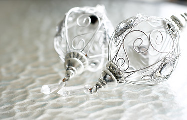 Image showing Sparkly silver colored Christmas baubles on glass table.