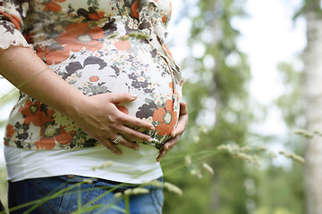 Image showing Woman holding her pregnant belly outdoors.