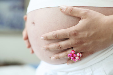 Image showing Woman holding her bare pregnant belly indoors.