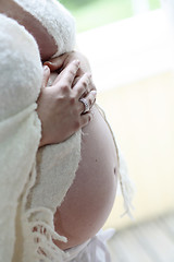 Image showing Woman holding her bare pregnant belly indoors.