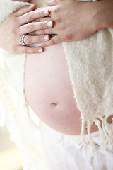 Image showing Woman holding her bare pregnant belly indoors.